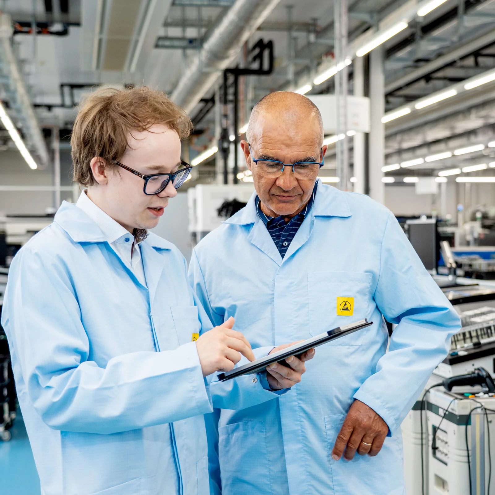 Elias Kettunen and Olivier Roy from Cicor discussing technical details on a tablet in a production environment.